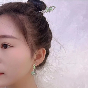Macro view of Chinese style silver hair pin and earring with green cat eye stones