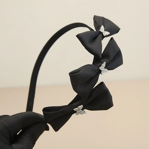 Nahaufnahme des schwarzen Satin-Haarreifs mit drei Schleifen und funkelnden Strass-Schmetterlingen