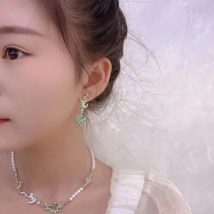 Detailed view of pearl necklace with green enamel accents and heart-shaped drop earrings
