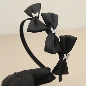 Detailansicht eines schwarzen Satin-Haarreifs mit drei 3D-Schleifen und Strass-Schmetterlingen
