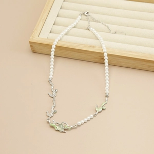 Detail of cat eye stone necklace with pearls and green heart pendant on wood tray