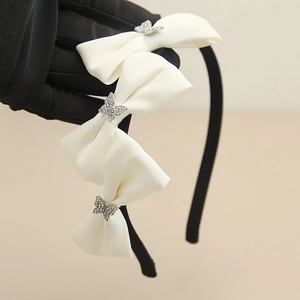 Detail eines schwarzen Haarreifs mit weißen Satinschleifen und silbernen Strass-Schmetterlingen