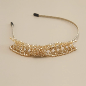 Macro detail of hand-woven champagne crystal beads on an elegant metallic hairband