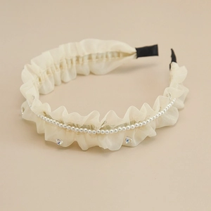 Dettaglio del cerchietto in tulle crema con catena di perle e cristalli scintillanti