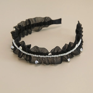 Dettaglio di un cerchietto in chiffon nero pieghettato con perle bianche e cristalli a cuore
