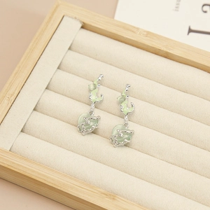 Macro view of silver lava drop earrings featuring green heart-shaped opal cat eye stones
