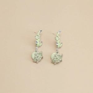 Detailed macro view of heart-shaped cat-eye stone and silver wavy metal earrings