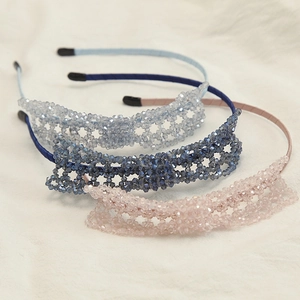Detailed view of handmade crystal beaded headbands in pastel pink and blue woven lace patterns