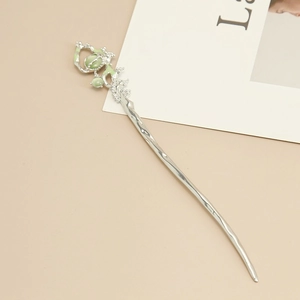 Detailed close-up of a vintage hair pin with green cat eye stones and enamel leaves