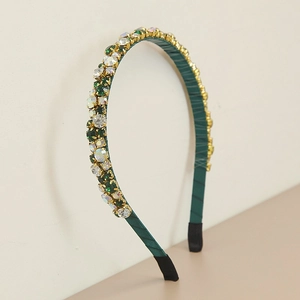 Detail of dark green rhinestone headband with gold metal claws and satin fabric