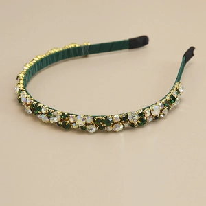 Detail of dark green headband with sparkling rhinestones and gold metal claw setting
