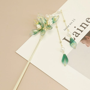 Detail of elegant gold hair stick with green resin flowers and pearl tassel drops