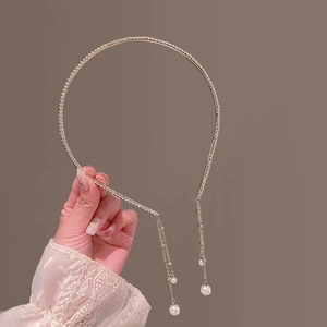 Détail d'un serre-tête doré avec pampilles de perles et fines chaînes métalliques élégantes