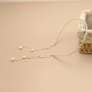 Détail d'un serre-tête doré avec de longues chaînes et des perles blanches élégantes