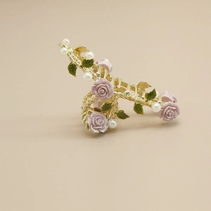 Detail of golden hair claw clip with purple roses, green leaves and small white pearls