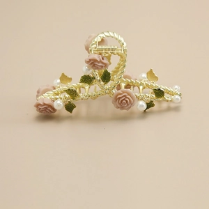 Detailed close-up of golden hair claw with pink resin roses and white faux pearls decoration