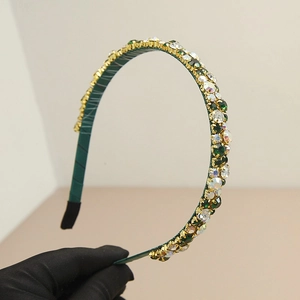 Detailed view of dark green gauze headband with emerald rhinestones in golden settings