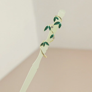 Detail view of translucent green resin hairpin with gold vine and enamel leaves
