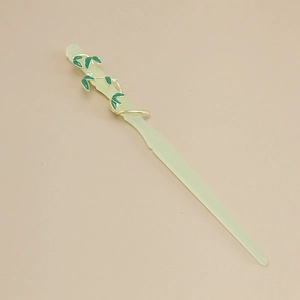 Detail of green resin flower hair stick with golden vines and bamboo texture engraving