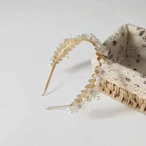 Détail du serre-tête de mariée à feuilles dorées avec fleurs et perles blanches