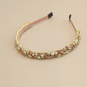 Detail of slim headband with pink and iridescent rhinestones on a gold frame
