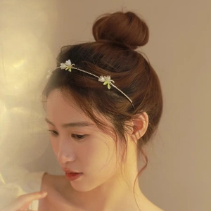 Detail view of thin flower headband with white enamel blossoms on a model’s profile