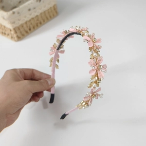 Détail du serre-tête à fleurs roses avec feuilles dorées, perles blanches et cristaux
