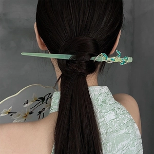 Detailed view of translucent green hair stick with enamel leaf and crystal accents