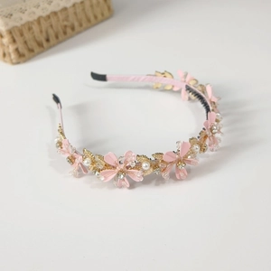Détail d'un serre-tête fleurs roses avec feuilles dorées, perles et cristaux sur fond blanc pur