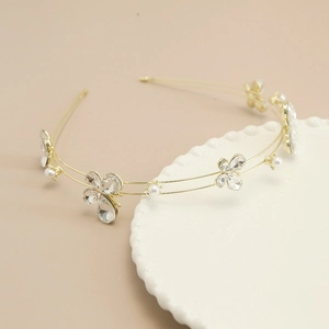 Detail of a golden double-layered headband with rhinestones, pearls and butterfly motifs