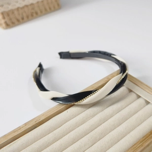 Detail of twisted black and beige hairband with small rhinestones on a wooden tray