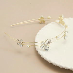 Detail of golden double-layer headband with crystal butterflies and pearls on a white tray