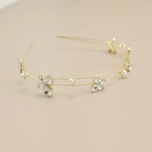 Detailed close-up of a double-layered golden headband with crystal bows and white pearls