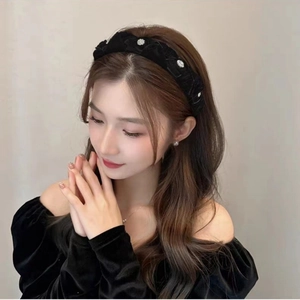Close-up of black velvet headband with floral rhinestone details worn by a model