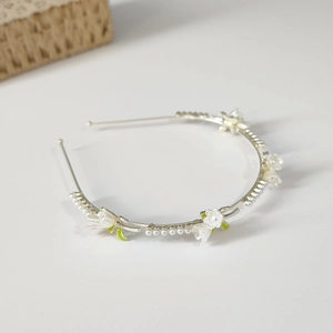Close-up of lily of the valley headband with white pearls and green enamel leaves