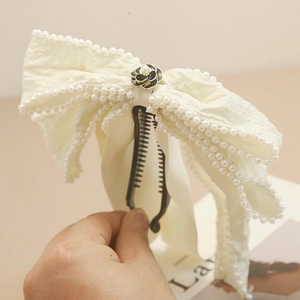 Detalle del clip de banana con lazo crema, bordes de perlas y rosa negra central