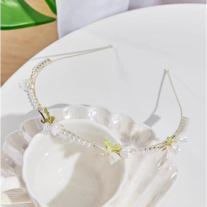 Detail of white flower petals and round pearls on a slim gold metal floral headband