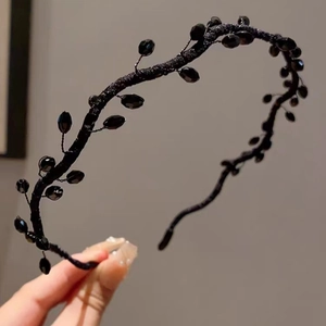 Detail of handcrafted black beaded headband featuring woven design and glossy glass crystals