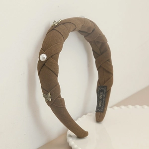 Detail of brown pleated headband with golden butterfly, pearls and hand made label