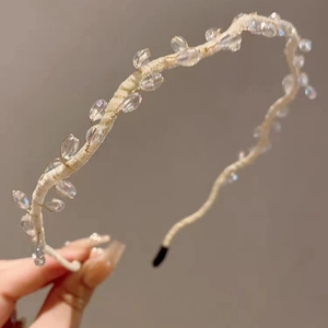 Close-up of elegant woven headband with sparkling clear crystals and beige fabric