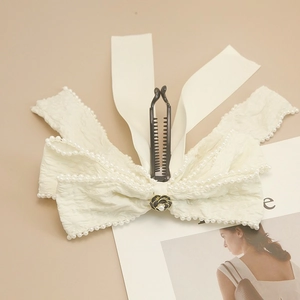 Pinza tipo banana con lazo blanco crema, bordes de perlas y dije de flor de rosa negra