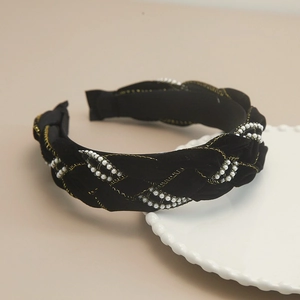 Close-up of black woven headband with white pearls and gold metallic thread details