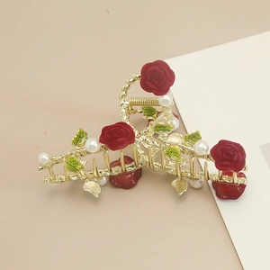 Elegante gouden haarklem met rode fluwelen rozen, groene bladeren en parels