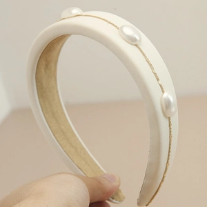 Detailed close-up of cream sponge headband with white pearls and gold chain link detail
