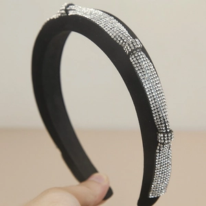 Detail of a wide black sponge headband featuring sparkling rhinestones and a twist knot design