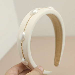 Detailed macro view of cream sponge headband with gold chain and faux pearl accents