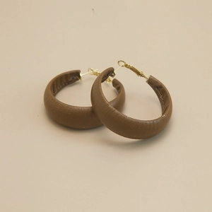 Vintage brown leather hoop earrings with gold metal hooks on a neutral background