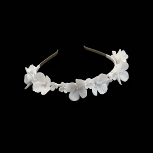 Dettaglio di fiori in ceramica bianca fatti a mano e perline su cerchietto da sposa