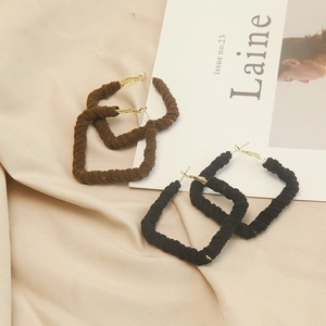 Detail of square woven fabric hoop earrings in black and brown with gold metal clasps