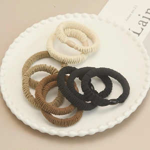 Gros plan d'élastiques à cheveux côtelés crème et marron sur une assiette en céramique
